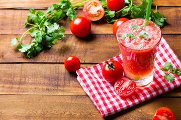 Gass of tomato smoothie, fresh tomatoes and cilantro on a dark wooden background . Vegetarian or healthy eating concept