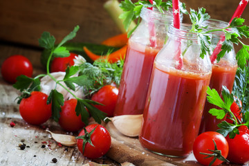 Spicy tomato juice in small bottles with straws, cherry tomatoes