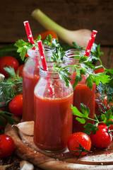 Spicy tomato juice in small bottles with straws, cherry tomatoes