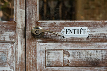 vintage entrance sign on wooden door (in French language)