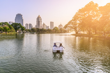 Womans playing pedal boats by urban lake in Bangkok.