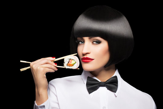 Woman with bob cut hair holding sushi with chopsticks