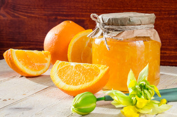 Банк апельсинового джема, несколько долек апельсина и нарцисс