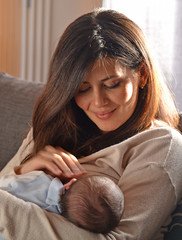 Madre latina compartiendo con su bebe en el hogar.