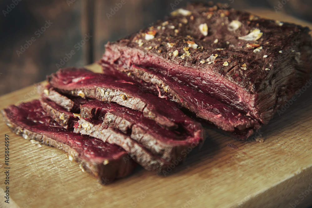 Wall mural closeup focus grilled meat thin sliced on wooden board