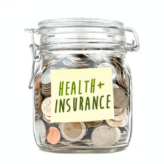 Savings money box coins stack thai baht with word "HEALTH+INSURANCE" on yellow stick note paper isolated on white background. Jar for savings full of coins. Piggy bank for saving money. Close up.