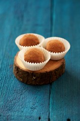 Homemade chocolate truffles in paper plates on navy blue wooden