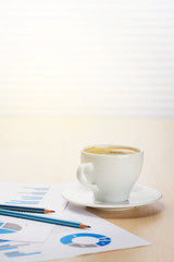 Office desk workplace with coffee and charts