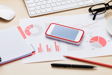 Office desk workplace with phone, charts and coffee