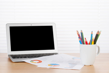 Office desk workplace with laptop, reports and pencils