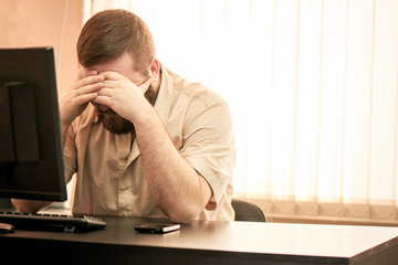 A man is sitting and holding his head