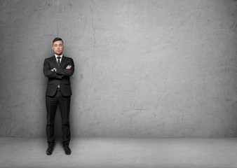Young man in business suit, standing front of the concrete wall background. Business concept