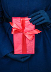 Woman hands showing  gift in red paper.