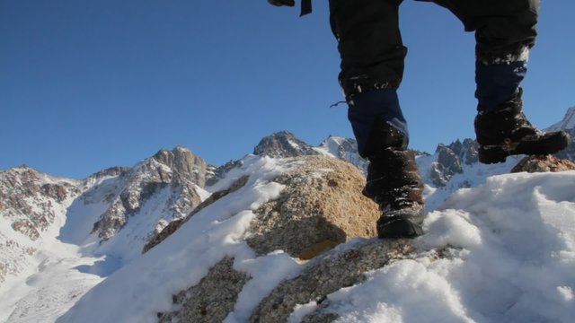 Close up of mans legs in heavy hiking boots standing on top of mountain