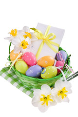 Easter basket with colorful eggs, present and daffodils on a whi