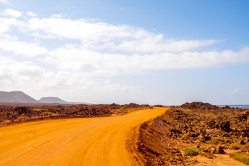 Fototapeta na wymiar Ground road at Corralejo dunes with mountains on the background on Fuerteventura island in Spain