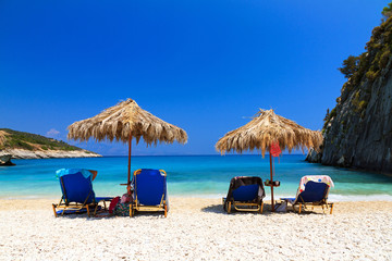 People are relaxing under a straw parasol on the beach at Xigia on the island of Zakynthos