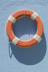 Red lifebuoy hanging on blue wall