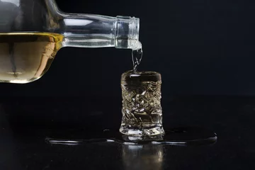 Papier peint photo autocollant rond Alcool alcohol from bottle to glass spilling on table 