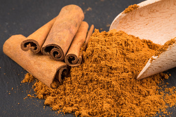 cinnamon sticks with powder and wooden spoon