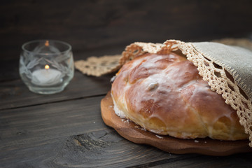 Easter bread with candle on wooden table, rustic style, selective focus