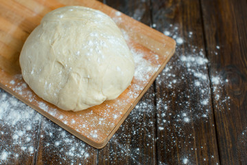 Ball of dough on a rustic wooden background with dusting of flou