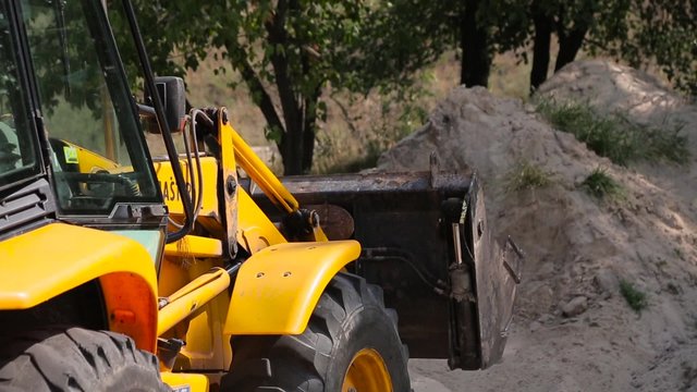 Yellow bulldozer scoop picks up.