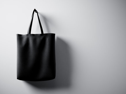 Photo black cotton textile bag hanging left side. Empty white wall background. Highly detailed texture, space for business message. Horizontal. 3d render