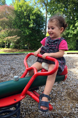 Little girl plays on a swing at the playground