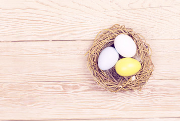 Easter colorful eggs in bird nest on wooden background