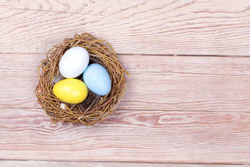 Easter colorful eggs in bird nest on wooden background