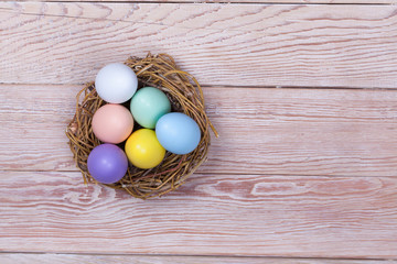 Easter colorful eggs in bird nest on wooden background
