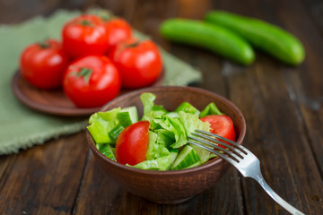 spring vegetables. tomatoes, cucumbers and lettuce on a wooden background