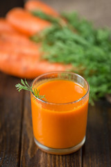 Carrot juice and fresh carrot on a wooden background