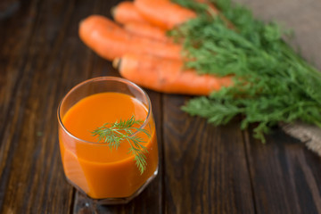 Carrot juice and fresh carrot on a wooden background