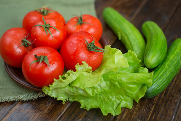 spring vegetables. tomatoes, cucumbers and lettuce on a wooden background