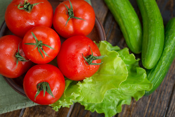 spring vegetables. tomatoes, cucumbers and lettuce on a wooden background