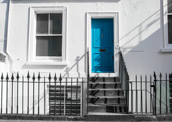 Blue front door on white wall with stairs and black metal fence - 105878136