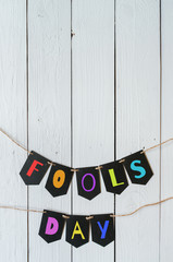 Fools day black banner colorful lettering on white barn wood rustic planks background. Fools day greeting postcard template. Space for text, copy.