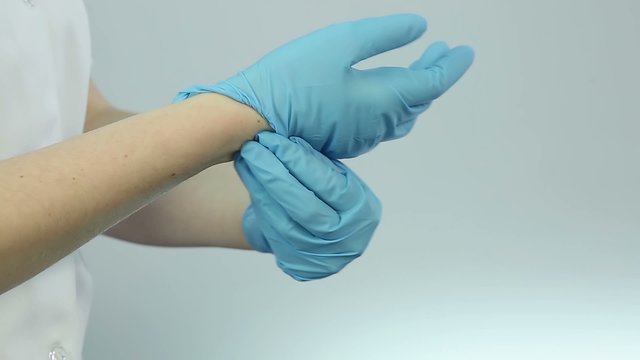 Nurse wearing medical gloves before treatment procedures, patient examination