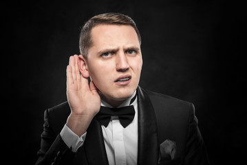 Man listening something over dark background.