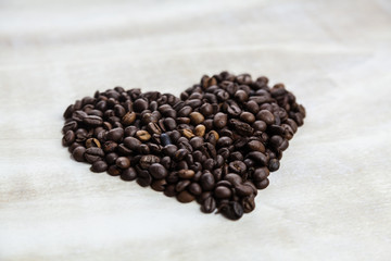 Heart from coffee beans on wooden background