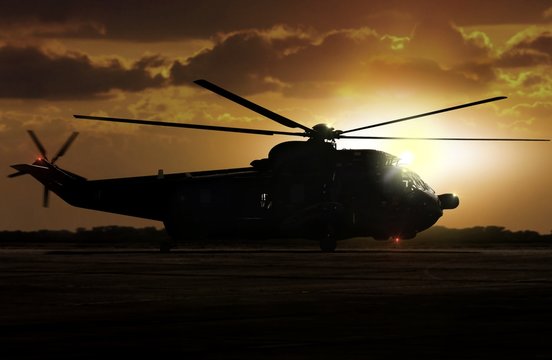 Military helicopter on airfield during sunset