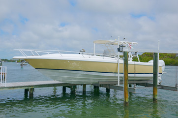 Expensive center console twin engine fishing boat on a lift at a dock