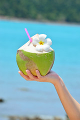  Coconut cocktails in woman hand against the turquoise sea