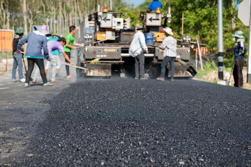 Worker operating asphalt paver machine during road construction