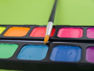 Акварельные яркие краски с кисточкой крупным планом