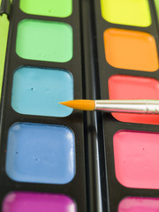 Акварельные яркие краски с кисточкой крупным планом