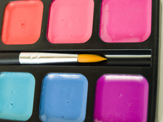 Акварельные яркие краски с кисточкой крупным планом