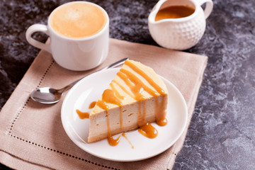 Slice of cheesecake with caramel sauce, cup of coffee